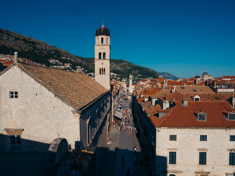 View of the Stradun street and the Franciscan Monastery bell tower with historic stone buildings and red tiled rooftops in Dubrovnik Dubrovnik Neretva County Croatia. View of the Stradun street and the Franciscan Monastery bell tower with historic stone buildings and red tiled rooftops in Dubrovnik Dubrovnik Neretva County Croatia.