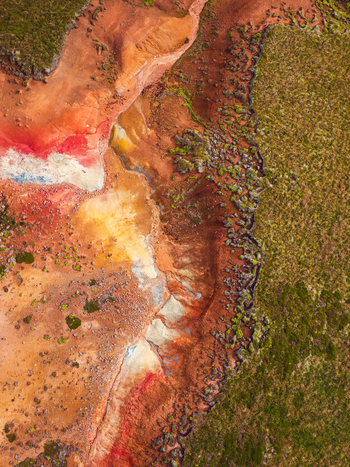 Aerial view of a vibrant geothermal landscape featuring colorful mineral deposits in shades of red orange and yellow contrasted by rugged volcanic rocks and patches of green moss Iceland. Aerial view of a vibrant geothermal landscape featuring colorful mineral deposits in shades of red orange and yellow contrasted by rugged volcanic rocks and patches of green moss Iceland.
