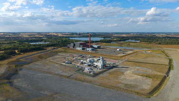 Aerial view of Millbrook Power Plant featuring its prominent red chimney and industrial infrastructure set within a landscape of fields and lakes in Stewartby England United Kingdom. Aerial view of Millbrook Power Plant featuring its prominent red chimney and industrial infrastructure set within a landscape of fields and lakes in Stewartby England United Kingdom.