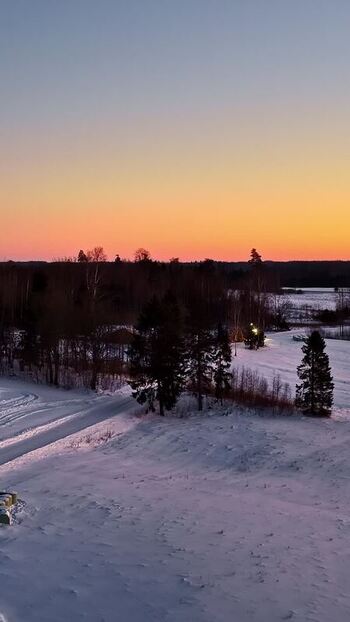 Aerial view of snowy landscape at sunset in Latvia.