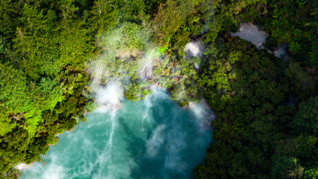 Aerial view of a vibrant turquoise pool steaming amidst lush green forest Waiotapu Thermal Wonderland Waikato Region New Zealand. Aerial view of a vibrant turquoise pool steaming amidst lush green forest Waiotapu Thermal Wonderland Waikato Region New Zealand.