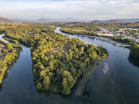 Aerial view of the Drin river flowing through lush green forests and rural landscapes near Shkoder Shkoder County Albania.