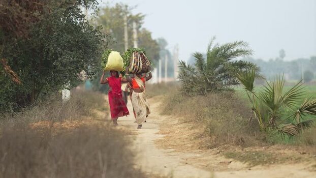 View of women carrying bundles on a rural path in Patna India.