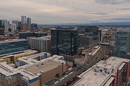 Aerial view of the Denver skyline featuring modern glass office buildings urban infrastructure and light rail tracks winding through the city center in Denver Colorado United States. Aerial view of the Denver skyline featuring modern glass office buildings urban infrastructure and light rail tracks winding through the city center in Denver Colorado United States.
