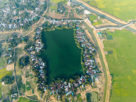 Aerial view of a serene lake embraced by homes and vibrant green fields a tranquil scene unfolds from above Sirajganj Rajshahi Division Bangladesh. Aerial view of a serene lake embraced by homes and vibrant green fields a tranquil scene unfolds from above Sirajganj Rajshahi Division Bangladesh.