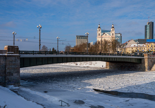 View of the Mindaugas Bridge over the frozen Neris River with the Church of St. Raphael the Archangel in the background in Vilnius Vilnius County Lithuania. View of the Mindaugas Bridge over the frozen Neris River with the Church of St. Raphael the Archangel in the background in Vilnius Vilnius County Lithuania.