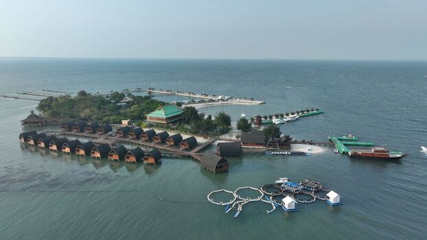 Aerial view of Pulau Lima Resort with overwater bungalows wooden walkways and fish farming cages in the sea in Kasemen Banten Indonesia. Aerial view of Pulau Lima Resort with overwater bungalows wooden walkways and fish farming cages in the sea in Kasemen Banten Indonesia.