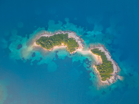Aerial view of the lush green Ksamil Islands surrounded by turquoise and deep blue waters of the Ionian Sea near Ksamil Vlore County Albania. Aerial view of the lush green Ksamil Islands surrounded by turquoise and deep blue waters of the Ionian Sea near Ksamil Vlore County Albania.