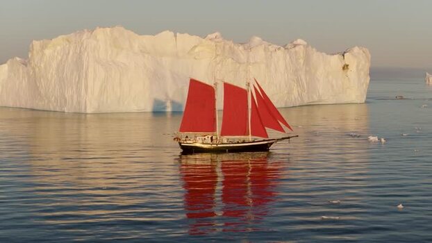 Aerial view of sailboat with red sails near iceberg Greenland. Aerial view of sailboat with red sails near iceberg Greenland.