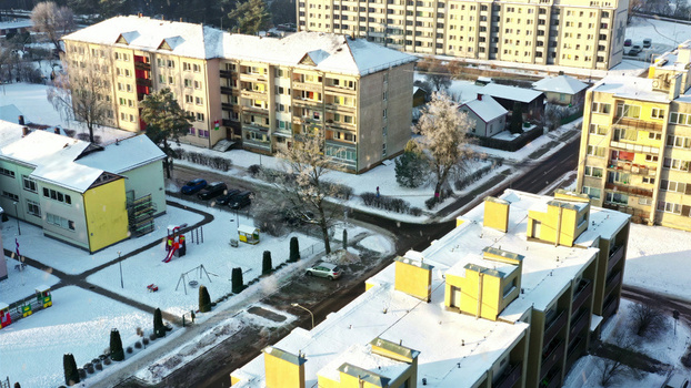 Aerial view of a snowy residential neighborhood featuring apartment buildings a small playground and frost covered trees in Latvia. Aerial view of a snowy residential neighborhood featuring apartment buildings a small playground and frost covered trees in Latvia.