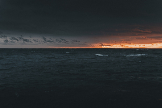 View of the dramatic sunset over the dark waters of the Baltic Sea at Saxby rannik featuring a vibrant orange horizon and deep blue storm clouds Saxby Laane maakond Estonia.