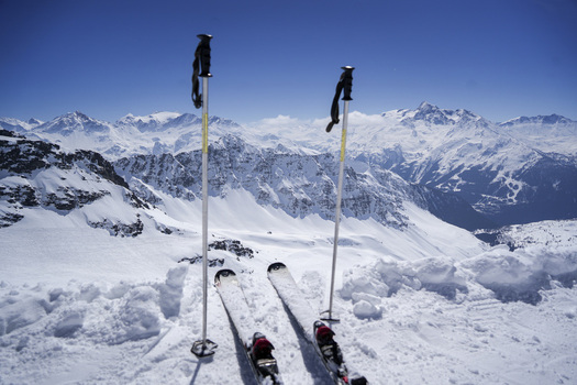 Aerial view of skis and poles on a snowy mountain ridge overlooking the French Alps at La Rosiere ski resort in Montvalezan Auvergne Rhone Alpes France.