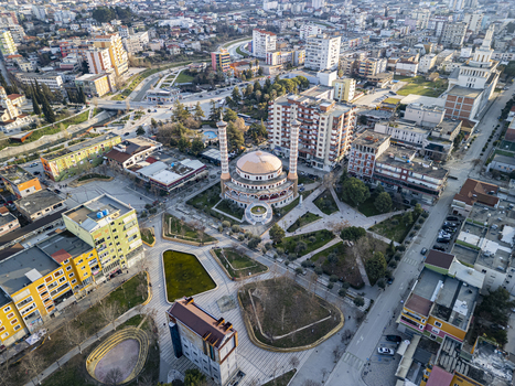 Aerial view of the Fier Mosque surrounded by urban buildings paved plazas and green spaces in the city center of Fier Fier County Albania. Aerial view of the Fier Mosque surrounded by urban buildings paved plazas and green spaces in the city center of Fier Fier County Albania.