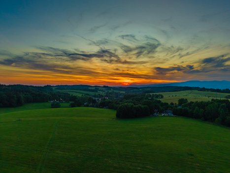 Aerial view of the rolling green hills and lush meadows of Horni Zdar under a vibrant sunset sky with wispy clouds Jindrichuv Hradec South Bohemian Region Czechia.