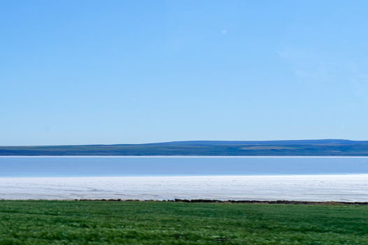 View of a vast salt lake with white crust and blue water under a clear sky with green fields in the foreground Ankara Ankara Turkiye. View of a vast salt lake with white crust and blue water under a clear sky with green fields in the foreground Ankara Ankara Turkiye.