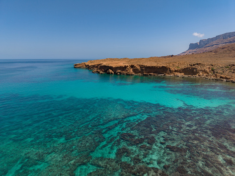 Aerial view of turquoise waters meeting rugged cliffs under a clear sky creating a mesmerizing contrast of color and texture Siqirah Yemen. Aerial view of turquoise waters meeting rugged cliffs under a clear sky creating a mesmerizing contrast of color and texture Siqirah Yemen.