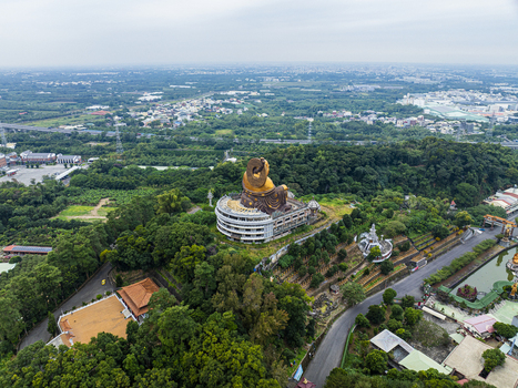 Aerial view of the Fo Guang Shan Buddha Museum featuring the giant golden Buddha statue surrounded by lush green hills and temple grounds in Jiuru Township Pingtung County Taiwan. Aerial view of the Fo Guang Shan Buddha Museum featuring the giant golden Buddha statue surrounded by lush green hills and temple grounds in Jiuru Township Pingtung County Taiwan.