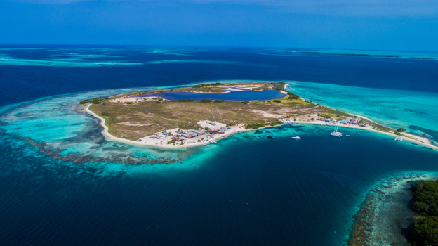 Aerial view of Los Roques archipelago featuring turquoise waters coral reefs and a small island with buildings and boats in Los Roques Dependencias Federales Venezuela. Aerial view of Los Roques archipelago featuring turquoise waters coral reefs and a small island with buildings and boats in Los Roques Dependencias Federales Venezuela.