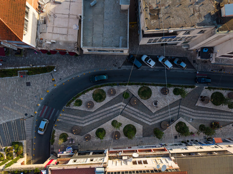 Aerial view of a modern urban square featuring geometric paving patterns circular planters and a curved street with parked cars in Kruje Durres County Albania.