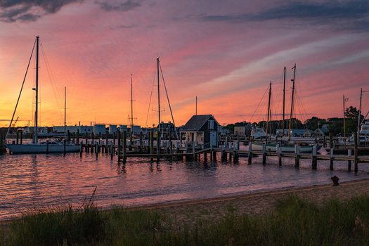 View of sailboats moored at wooden docks in Martha s Vineyard harbor under a vibrant sunset sky Edgartown Massachusetts United States.