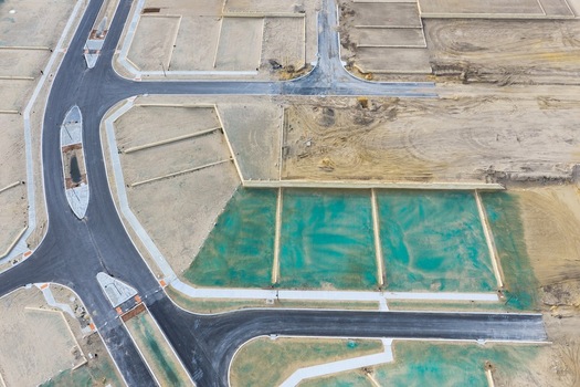 Aerial view of a new residential development site featuring newly paved roads and plots prepared for construction with green erosion control netting in Perth Western Australia Australia. Aerial view of a new residential development site featuring newly paved roads and plots prepared for construction with green erosion control netting in Perth Western Australia Australia.