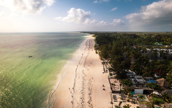 Aerial view of the shoreline where turquoise water meets the white sand beach flanked by lush green trees Paje Unguja South Region Tanzania. Aerial view of the shoreline where turquoise water meets the white sand beach flanked by lush green trees Paje Unguja South Region Tanzania.
