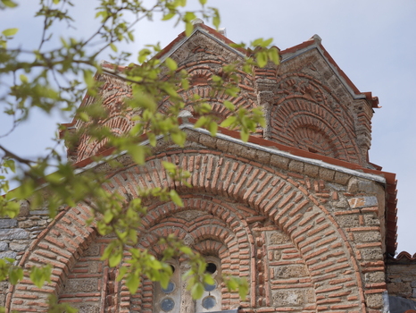 View of the intricate brickwork and architectural details of the Church of St. John at Kaneo framed by green leaves in Ohrid Municipality of Ohrid North Macedonia. View of the intricate brickwork and architectural details of the Church of St. John at Kaneo framed by green leaves in Ohrid Municipality of Ohrid North Macedonia.