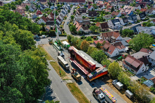 Forchheim Germany 27 July 2023 Aerial view of the setup for the Annafest festival with large trucks and fairground trailers parked near a residential neighborhood and lush trees. Forchheim Germany 27 July 2023 Aerial view of the setup for the Annafest festival with large trucks and fairground trailers parked near a residential neighborhood and lush trees.