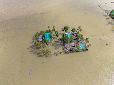 Aerial view of a small island with houses and trees surrounded by floodwaters in Banshkhali Upazila Chittagong Division Bangladesh. Aerial view of a small island with houses and trees surrounded by floodwaters in Banshkhali Upazila Chittagong Division Bangladesh.