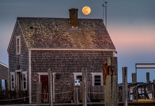 View of Martha s Vineyard featuring a weathered shingle building with a full moon rising behind the chimney at twilight in Edgartown Massachusetts United States.