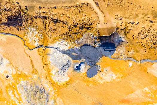 Aerial view of Hverir geothermal field with bubbling mud pots steaming fumaroles and vibrant mineral rich soil in the barren landscape of Reykjahlid Thingeyjarsveit Iceland.