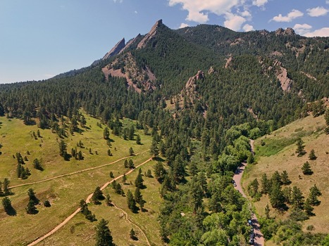 Aerial view of Chautauqua Park featuring the iconic Flatirons rock formations lush pine forests winding hiking trails and a clear blue sky in Boulder Colorado United States. Aerial view of Chautauqua Park featuring the iconic Flatirons rock formations lush pine forests winding hiking trails and a clear blue sky in Boulder Colorado United States.