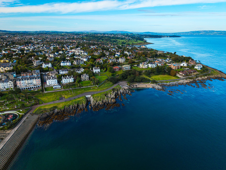 Aerial view of Bangor Harbour and Town featuring coastal residential areas green spaces rocky shoreline and blue waters in Bangor Northern Ireland United Kingdom.