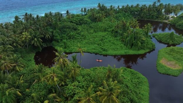 Aerial view of a person on a paddleboard in a dark tropical lake Maldives. Aerial view of a person on a paddleboard in a dark tropical lake Maldives.