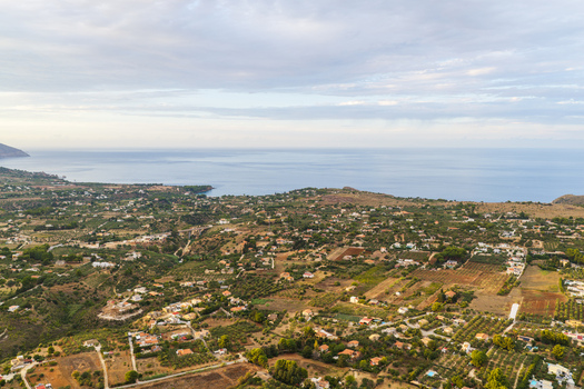 Aerial view of the Riserva Naturale Orientata dello Zingaro coastline featuring rolling hills olive groves scattered rural buildings and the Mediterranean Sea in San Vito Lo Capo Sicilia Italy. Aerial view of the Riserva Naturale Orientata dello Zingaro coastline featuring rolling hills olive groves scattered rural buildings and the Mediterranean Sea in San Vito Lo Capo Sicilia Italy.