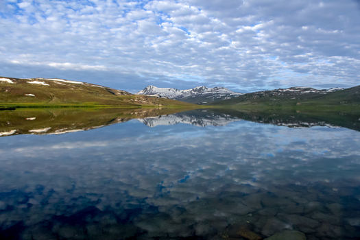 View of Sheosar Lake with its calm waters reflecting the snow capped mountains and a dramatic cloudy sky in Skardu Pakistan. View of Sheosar Lake with its calm waters reflecting the snow capped mountains and a dramatic cloudy sky in Skardu Pakistan.