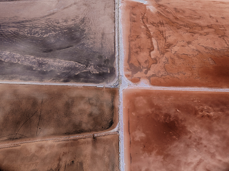 Aerial view of the geometric salt evaporation ponds with reddish brown water and white salt crusts divided by narrow paths in Cagliari Sardinia Italy. Aerial view of the geometric salt evaporation ponds with reddish brown water and white salt crusts divided by narrow paths in Cagliari Sardinia Italy.