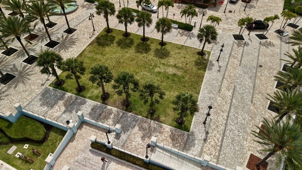 Aerial view of a paved plaza with palm trees a central green lawn and stone walkways in Palm Beach County Florida United States.