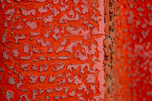 View of peeling vibrant red paint on a textured surface creates an abstract landscape of color and decay Dronten Flevoland Netherlands. View of peeling vibrant red paint on a textured surface creates an abstract landscape of color and decay Dronten Flevoland Netherlands.