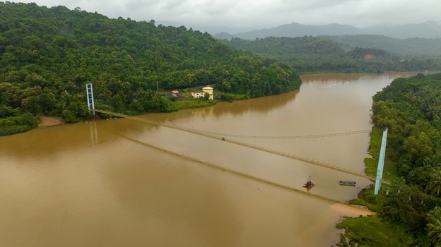 Aerial view of the suspension bridge spanning the Sharavathi River surrounded by lush green hills and dense vegetation in Honnavar Karnataka India.