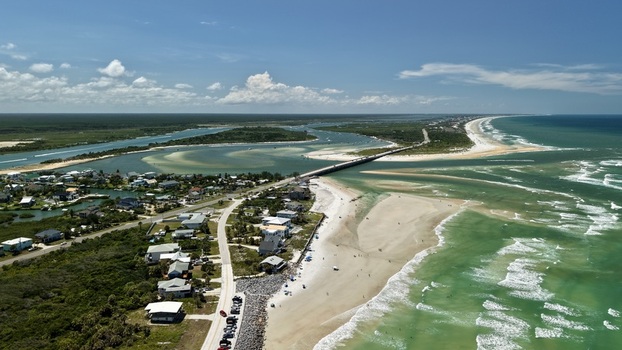 Aerial view of Matanzas Inlet featuring the bridge coastal homes sandy beach and turquoise ocean waters in St. Johns County Florida United States. Aerial view of Matanzas Inlet featuring the bridge coastal homes sandy beach and turquoise ocean waters in St. Johns County Florida United States.