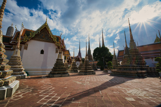 View of the ornate stupas at Wat Phra Chetuphon Wimon Mangkhalaram Rajwaramahawihan with a tiled courtyard under a bright sky in Krung Thep Maha Nakho Thailand. View of the ornate stupas at Wat Phra Chetuphon Wimon Mangkhalaram Rajwaramahawihan with a tiled courtyard under a bright sky in Krung Thep Maha Nakho Thailand.