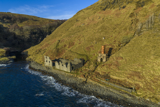 Aerial view of the historic stone ruins of the old diatomite works nestled against a steep grassy hillside on the rocky coastline Isle of Skye Scotland United Kingdom. Aerial view of the historic stone ruins of the old diatomite works nestled against a steep grassy hillside on the rocky coastline Isle of Skye Scotland United Kingdom.