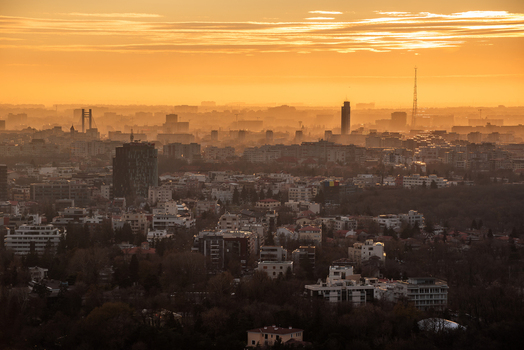 View of the Bucharest skyline bathed in the warm golden light of sunset with hazy atmosphere over the urban buildings in Bucharest Bucharest Romania. View of the Bucharest skyline bathed in the warm golden light of sunset with hazy atmosphere over the urban buildings in Bucharest Bucharest Romania.