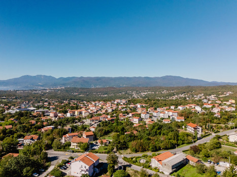 Aerial view of the village of Marcelji with red roofed houses lush greenery and winding roads set against a backdrop of mountains in Marcelji Primorje Gorski Kotar Croatia.