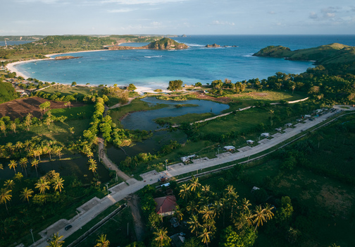 Aerial view of turquoise waters meet pristine white sands cradled by verdant hills under a soft sky Pantai Tanjung Aan West Nusa Tenggara Indonesia. Aerial view of turquoise waters meet pristine white sands cradled by verdant hills under a soft sky Pantai Tanjung Aan West Nusa Tenggara Indonesia.