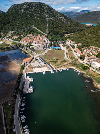 Aerial view of the historic town of Ston with its famous defensive walls climbing the hillside the harbor with moored boats and salt pans Ston Dubrovnik Neretva County Croatia.