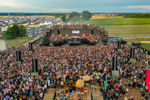 Herzogenaurach Germany 24 July 2025 Aerial view of the Open Beatz Festival featuring a massive crowd gathered in front of the main stage with a large camping area and green fields.
