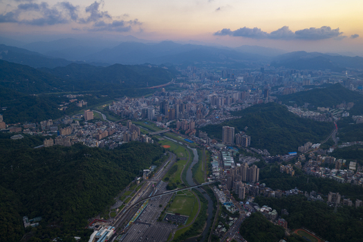 Aerial view of the sprawling cityscape of Taipei City nestled among green mountains at dusk featuring a winding river and high rise buildings in Taipei City Taiwan. Aerial view of the sprawling cityscape of Taipei City nestled among green mountains at dusk featuring a winding river and high rise buildings in Taipei City Taiwan.