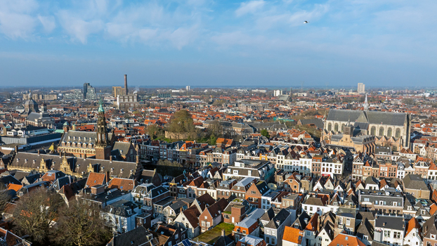 Aerial view of the historic city center of Leiden with dense red tiled rooftops canals and the prominent Hooglandse Kerk under a clear blue sky in Leiden South Holland Netherlands.